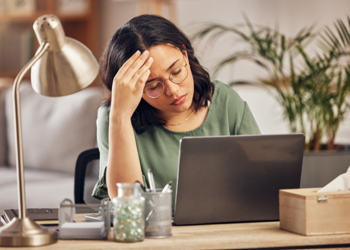 Overwhelmed content creator examining financial documents, symbolizing common bookkeeping errors at a work desk.