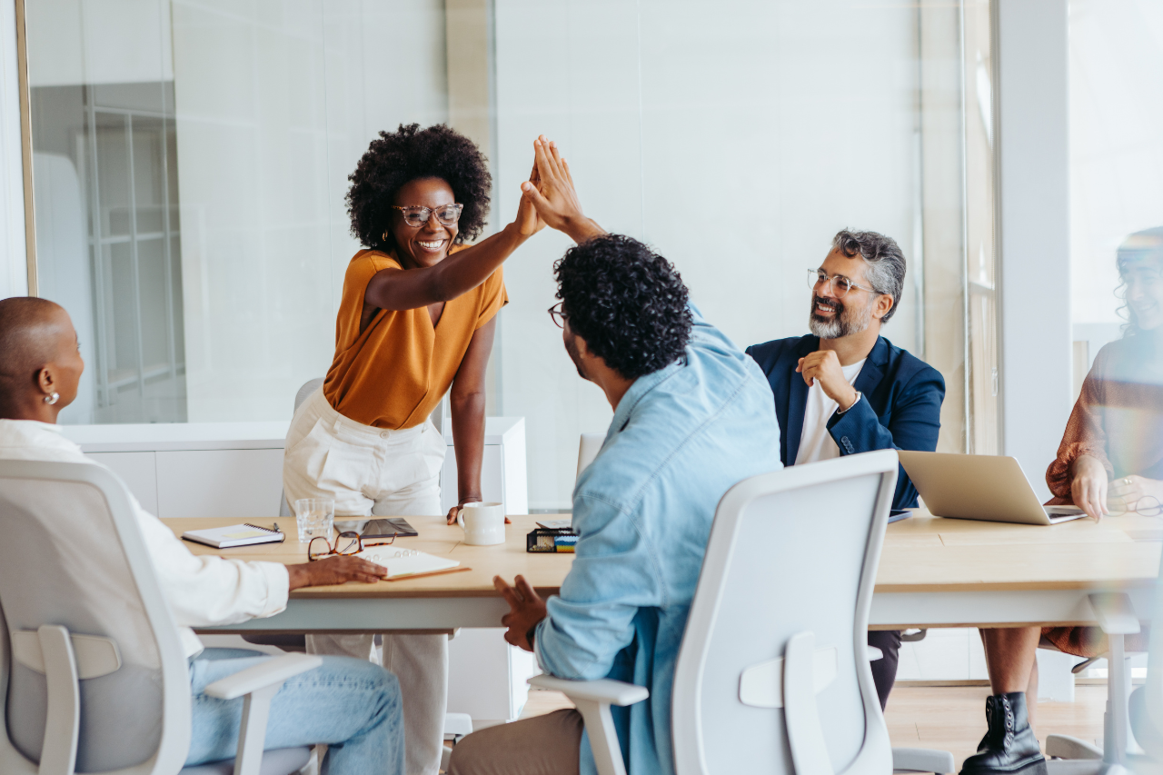 Startup team members high-fiving, exuding enthusiasm in an accounting strategy session.